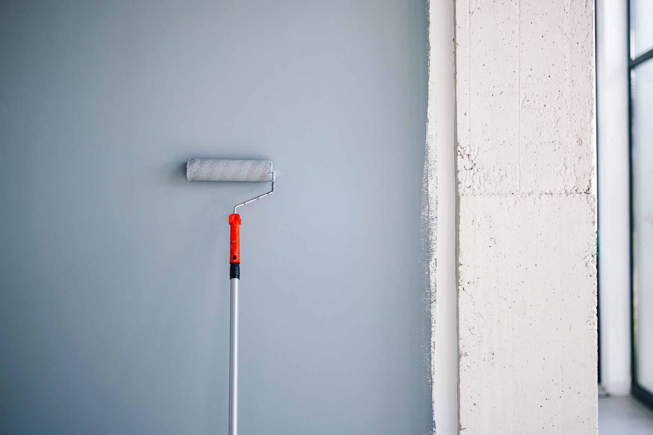 Professional painter applying paint to a clean interior wall
